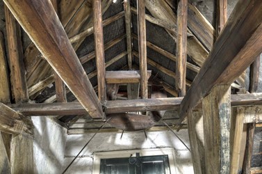 <p>Het hijsrad op de zolder van het voorhuis dateert waarschijnlijk uit de 19e eeuw. Ten behoeve van de hijsvoorziening is het middendeel van de gevel hoger opgetrokken en is de kapconstructie ter plaatse aangepast. </p>
